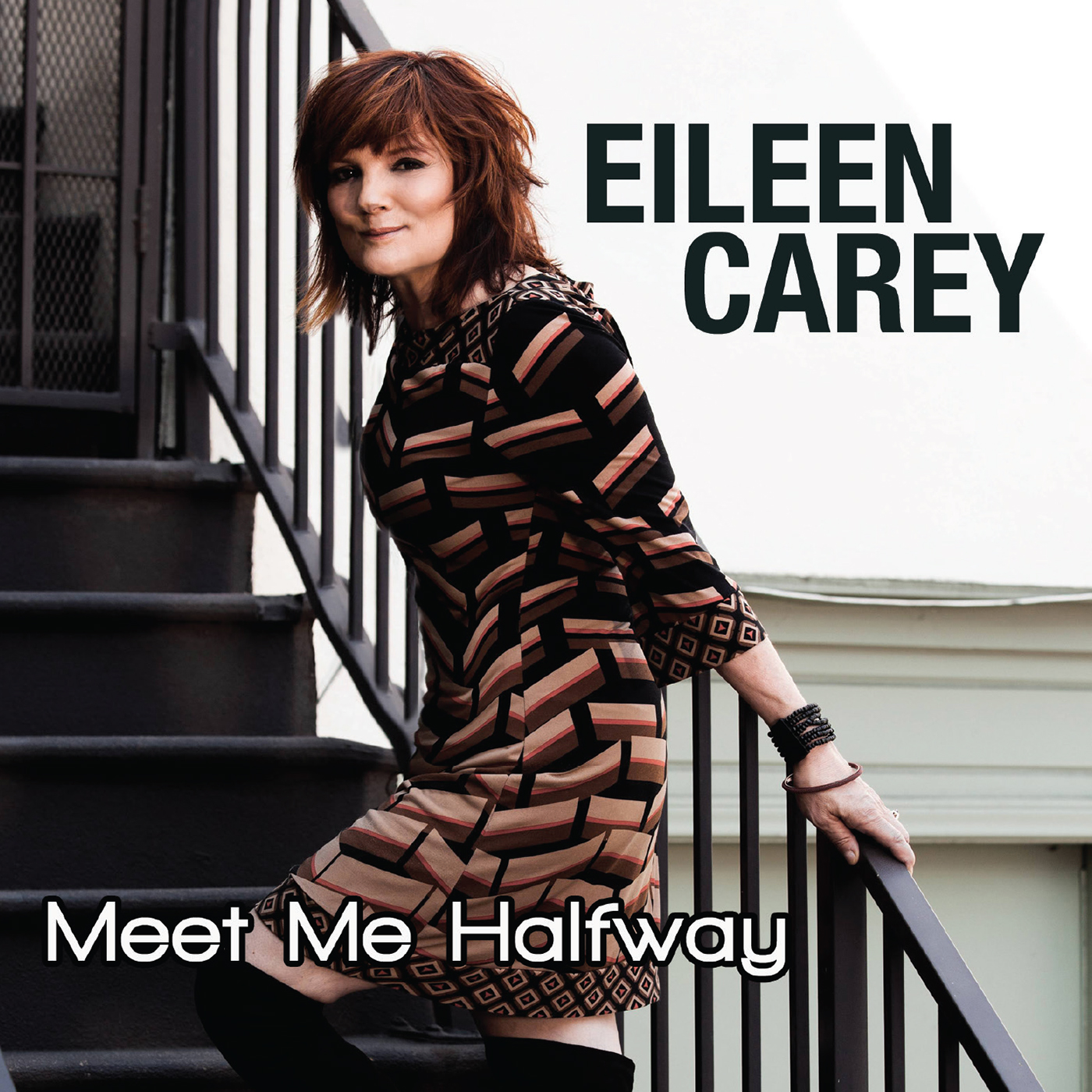 Eileen Carey wearing brown plaid dress standing on stairs