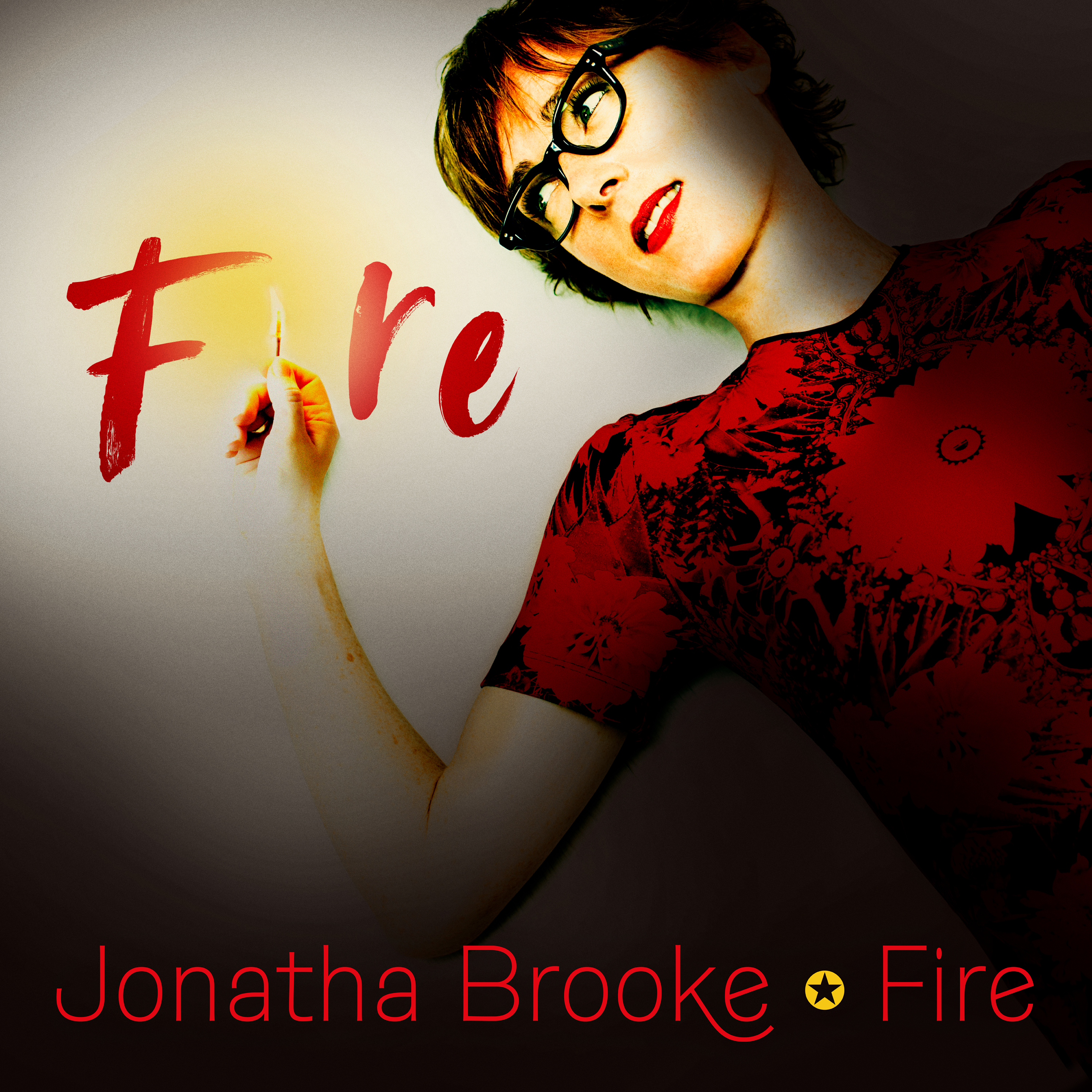 Jonatha Brooke wearing red and black dress holding lit match